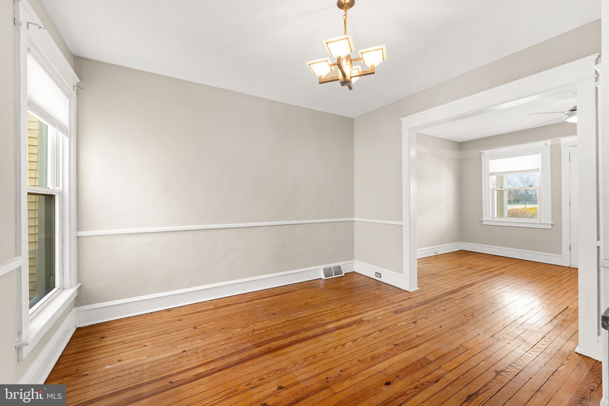 1441 Lawrence Road Havertown, PA 19083 - Photo 7 of 13 an empty room with wooden floor chandelier and windows