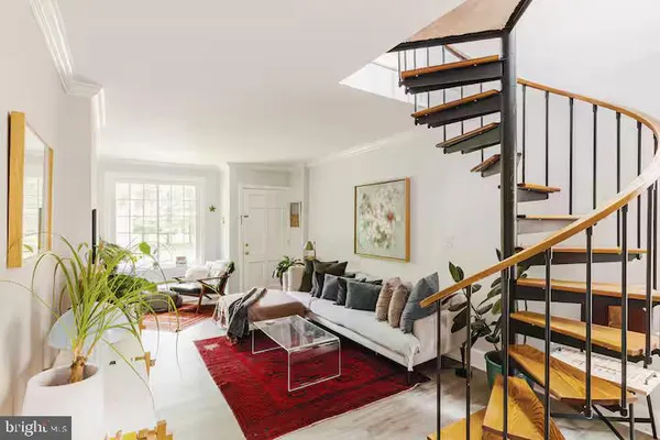 a living room with furniture stairs and a potted plant