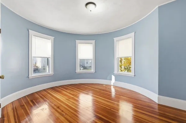 a view of an empty room with window and wooden floor