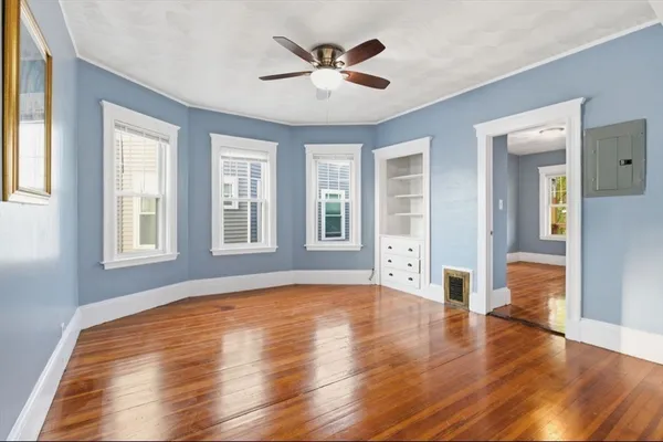 a view of an empty room with window and wooden floor