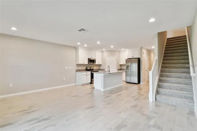 a view of kitchen with kitchen island white cabinets and stainless steel appliances