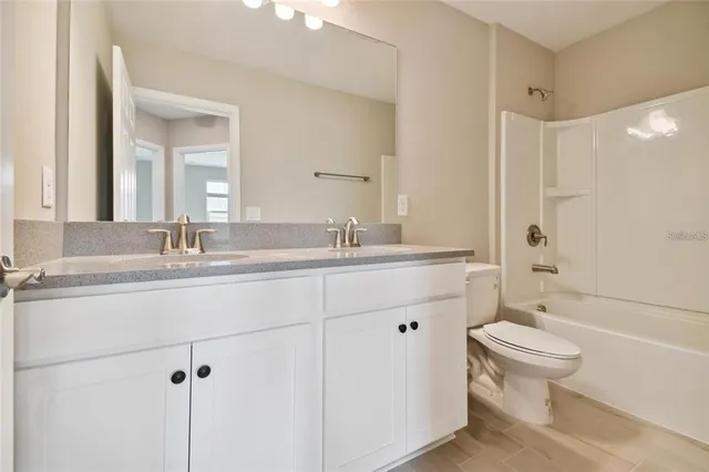 a bathroom with a double vanity sink toilet mirror and shower
