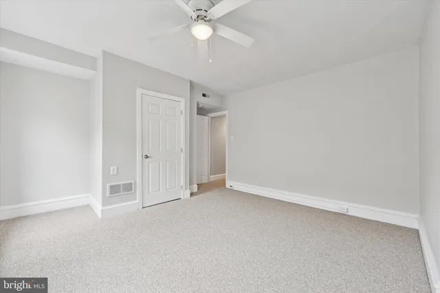 an empty room with a ceiling fan and a window