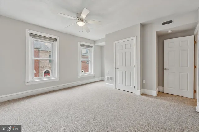 an empty room with windows and ceiling fan
