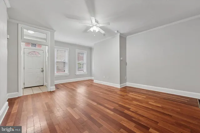 a view of an empty room with wooden floor and window