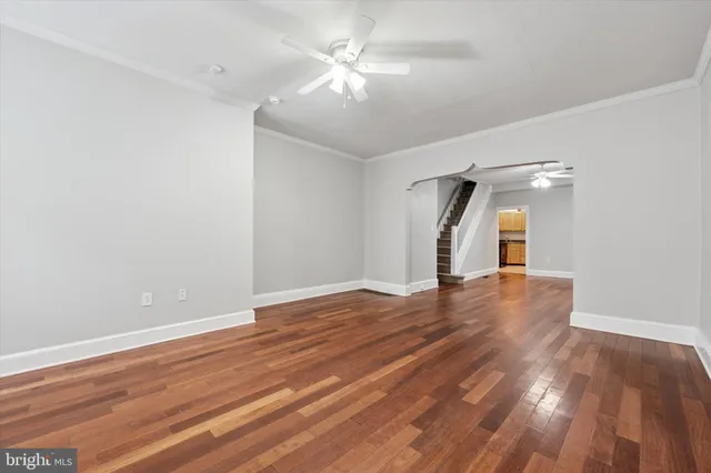 a view of empty room with wooden floor and ceiling fan