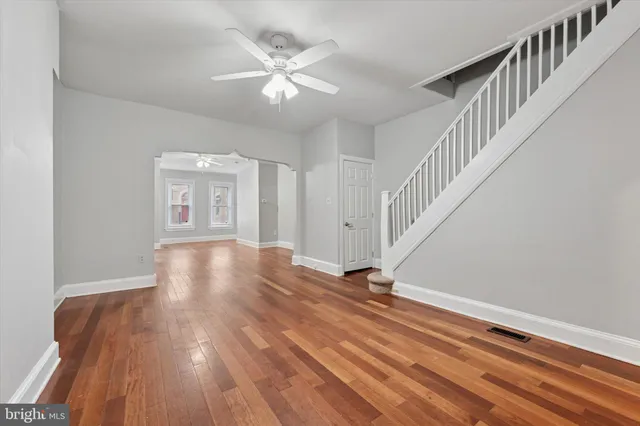a view of an empty room with wooden floor and a chandelier