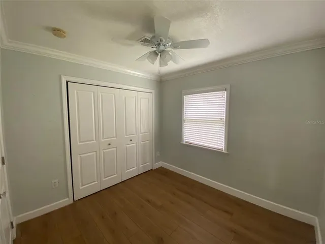 an empty room with wooden floor closet and windows