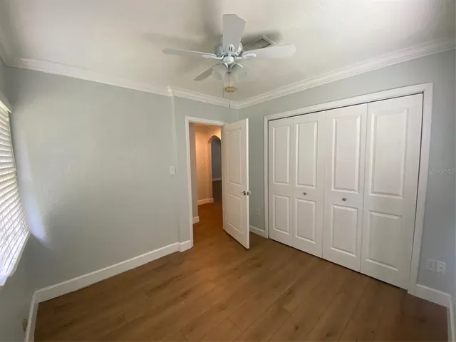 an empty room with wooden floor fan and windows