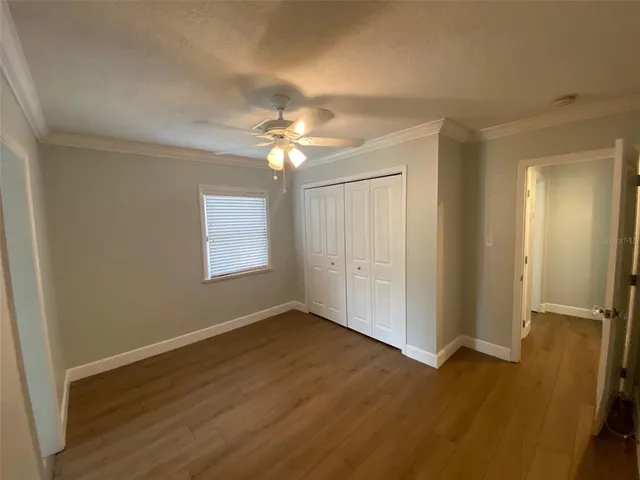 an empty room with wooden floor chandelier fan and windows