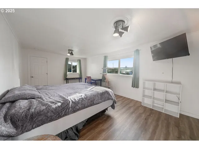 a bedroom with a bed and a flat tv screen on dresser