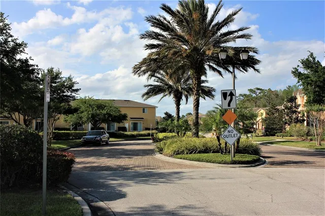 a view of a street with a cars parked and small yard
