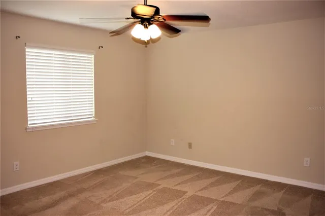 an empty room with a window and a fan