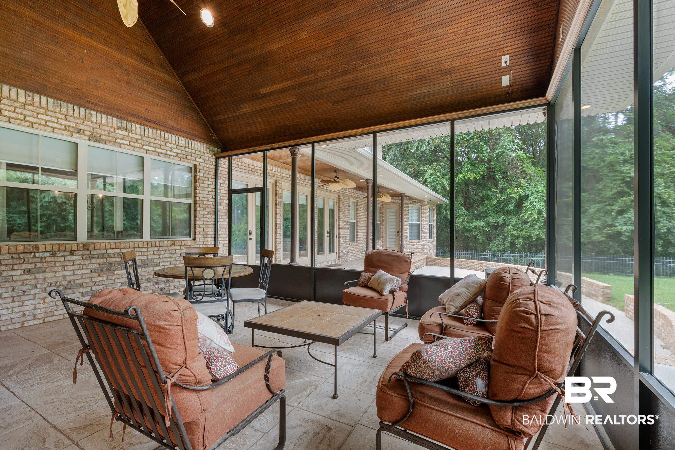 30463 Dolive Ridge Daphne, AL 36527 - Photo 21 of 58 Screened outdoor living area with a vaulted wood-finish ceiling, brick exterior wall, and light-toned tile flooring