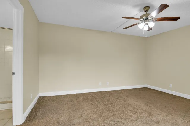 an empty room with a chandelier fan and a window