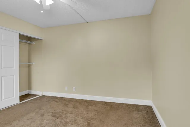 an empty room with a ceiling fan and carpet