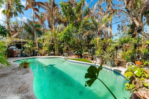 a swimming pool with lawn chairs under an umbrella