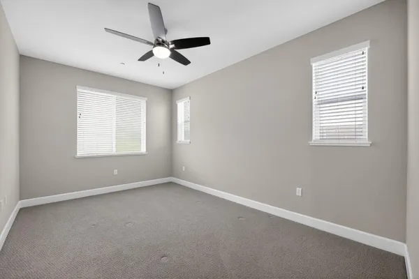 an empty room with a window and a ceiling fan