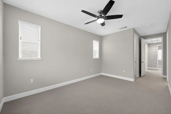 an empty room with a window and a ceiling fan