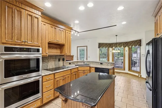 a kitchen with stainless steel appliances granite countertop a stove a sink and a refrigerator