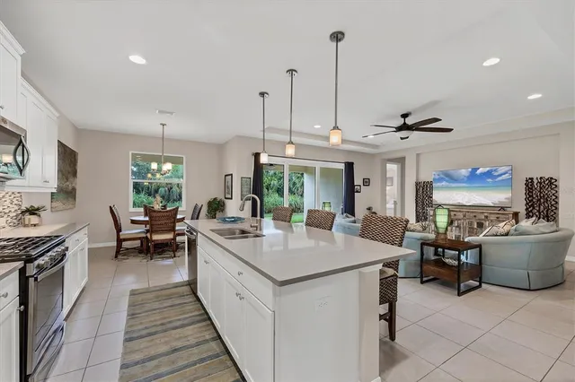 a kitchen with stainless steel appliances kitchen island a refrigerator a stove a sink and chairs