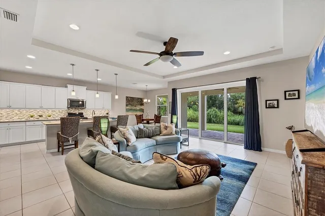 a kitchen with stainless steel appliances kitchen island granite countertop a refrigerator a stove a sink a dining table and chairs with wooden floor