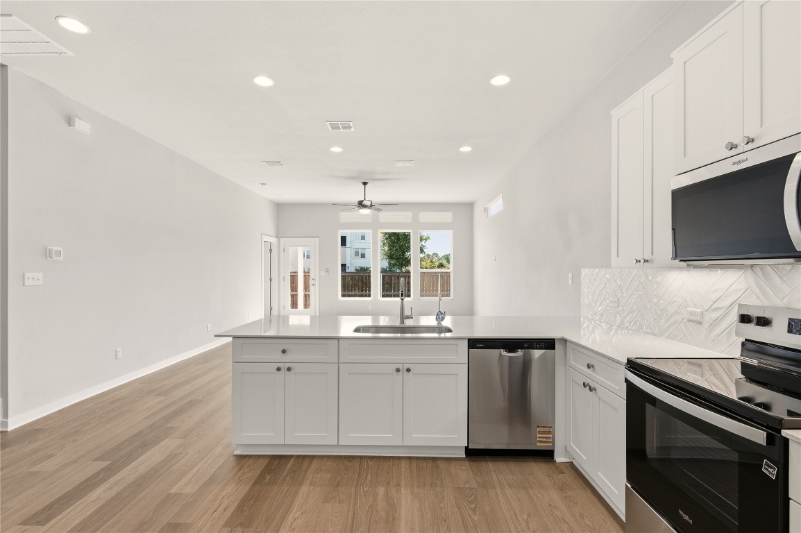 2206 Luna Azul View, Unit 78 Round Rock, TX 78664 - Photo 6 of 31 Kitchen with stainless steel appliances, a peninsula, white cabinetry, tasteful backsplash, and recessed lighting