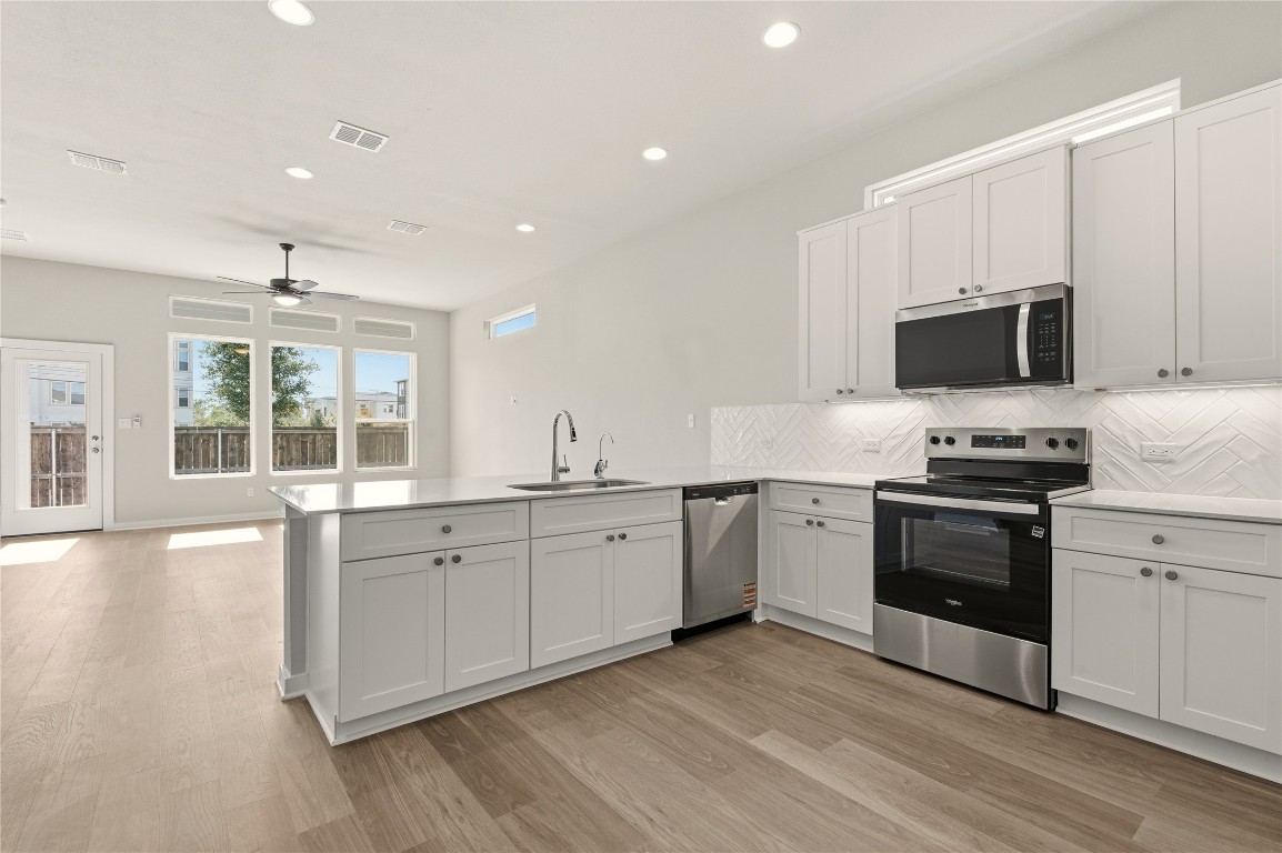 2206 Luna Azul View, Unit 78 Round Rock, TX 78664 - Photo 7 of 31 Kitchen featuring stainless steel appliances, recessed lighting, white cabinets, tasteful backsplash, and a peninsula