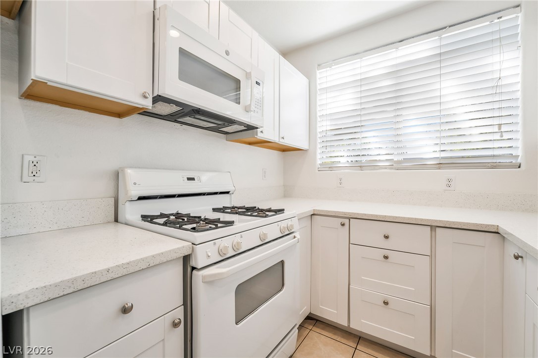 2201 Ramsgate Drive, Unit 811 Henderson, NV 89074 - Photo 14 of 36 A well-appointed kitchen features white cabinetry and light countertops, offering ample workspace and a modern aesthetic.