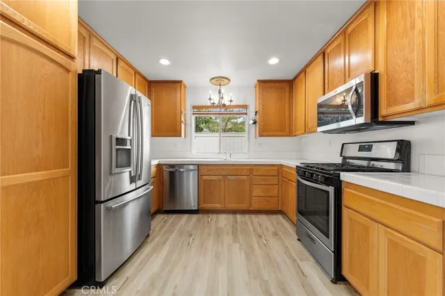 a kitchen with stainless steel appliances granite countertop a refrigerator a stove top oven and sink