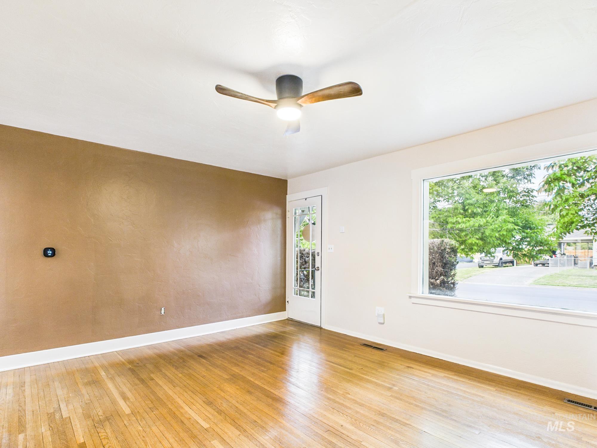 3422 6th Street Lewiston, ID 83501 - Photo 7 of 43 Spacious room featuring wood-finish flooring, a large picture window, and a ceiling fan with light fixture