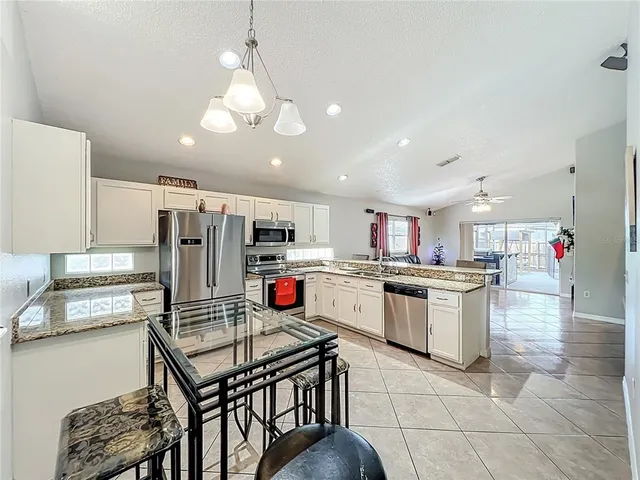a open kitchen with stainless steel appliances granite countertop a stove top oven a sink dishwasher and white cabinets with wooden floor