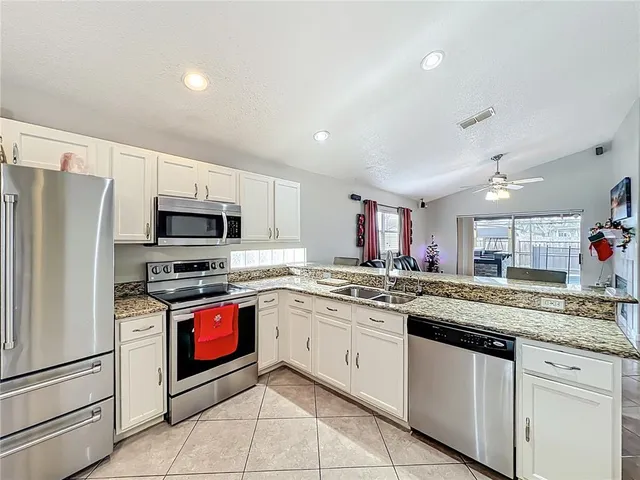 a kitchen with stainless steel appliances granite countertop a sink and dishwasher a refrigerator with white cabinets