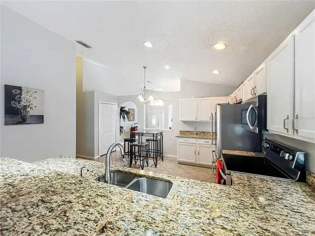 a kitchen with stainless steel appliances kitchen island granite countertop a sink refrigerator and cabinets