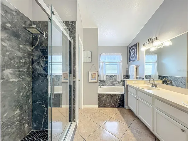 a large bathroom with a tub sink shower and mirror