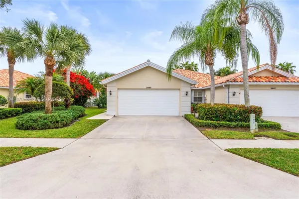a front view of a house with a garden and palm trees