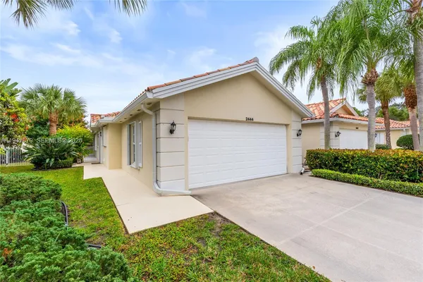 front view of house with a yard and palm trees