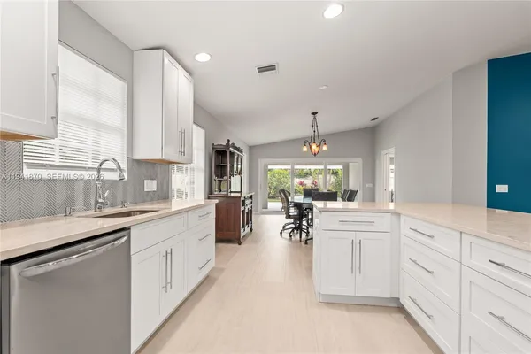 a large white kitchen with white cabinets and chandelier