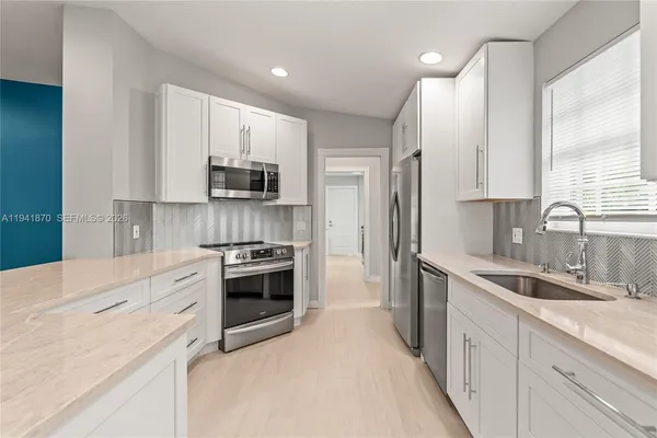 a kitchen with granite countertop white cabinets and stainless steel appliances