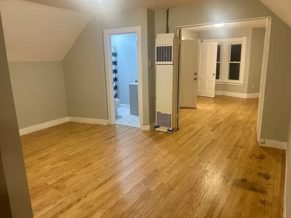 an empty room with wooden floor and bathroom