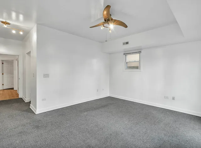 an empty room with a chandelier fan and windows