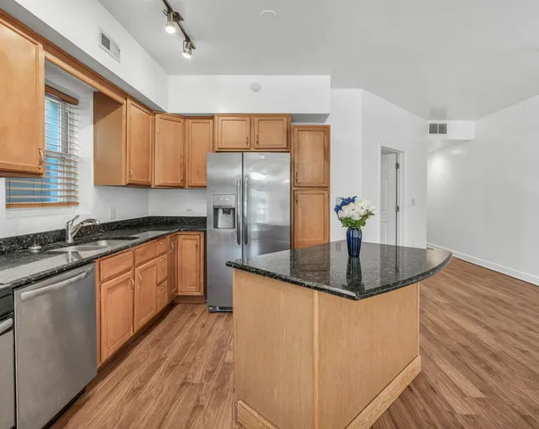 a kitchen with stainless steel appliances granite countertop a sink a stove and refrigerator