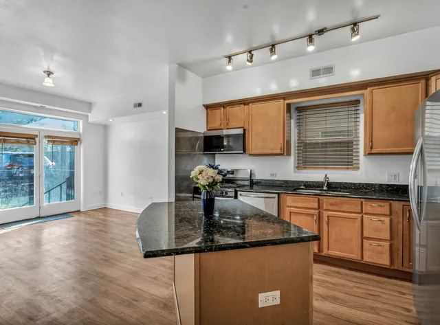 a kitchen with granite countertop a sink a counter top space cabinets and stainless steel appliances