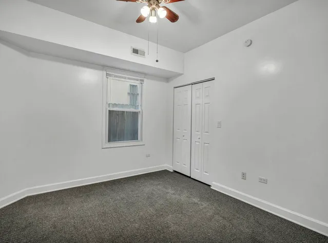 an empty room with a ceiling fan and a window
