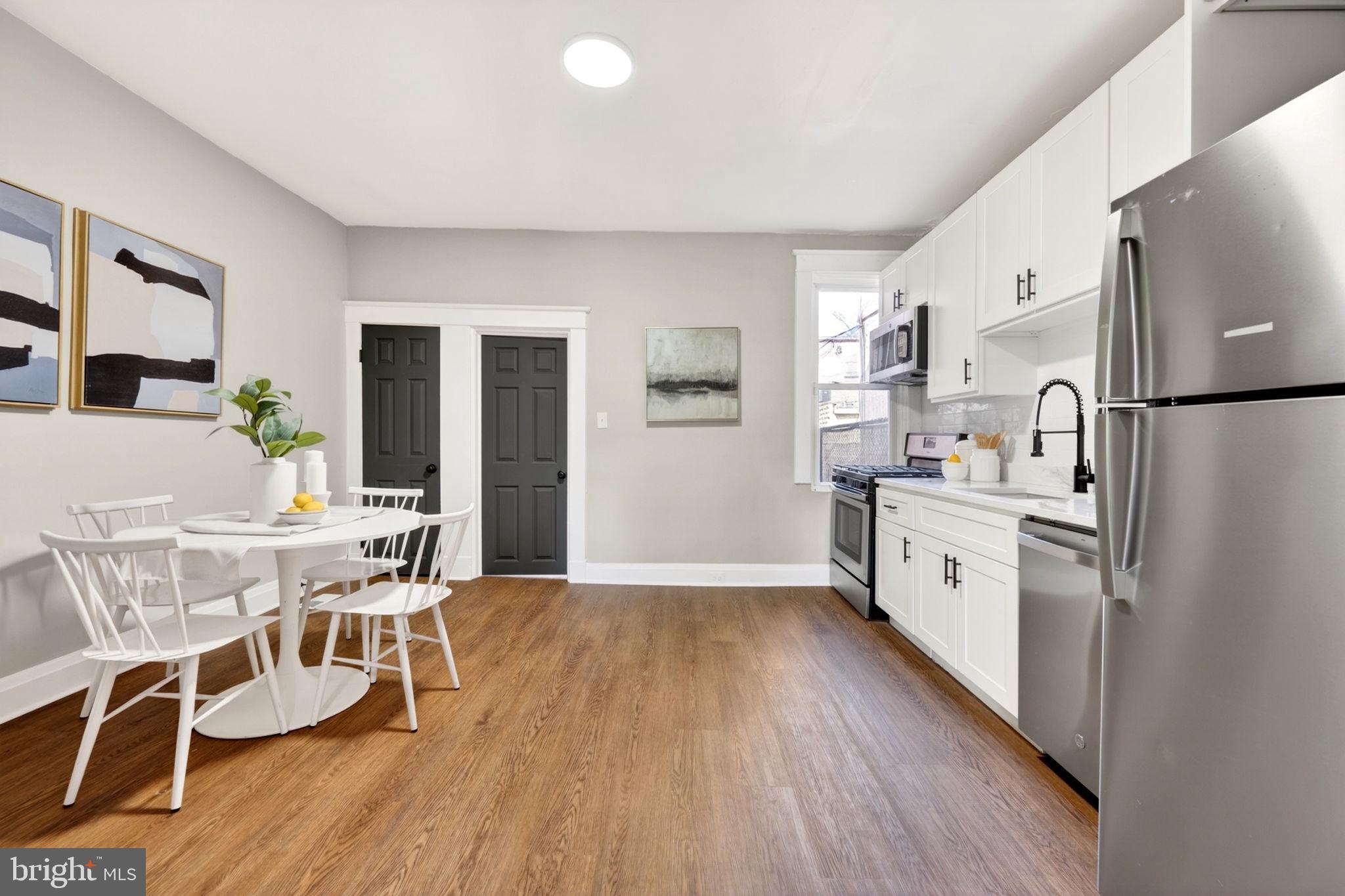 1358 Homestead Street Baltimore, MD 21218 - Photo 10 of 35 a kitchen with stainless steel appliances a refrigerator a stove a dining table and chairs with wooden floor