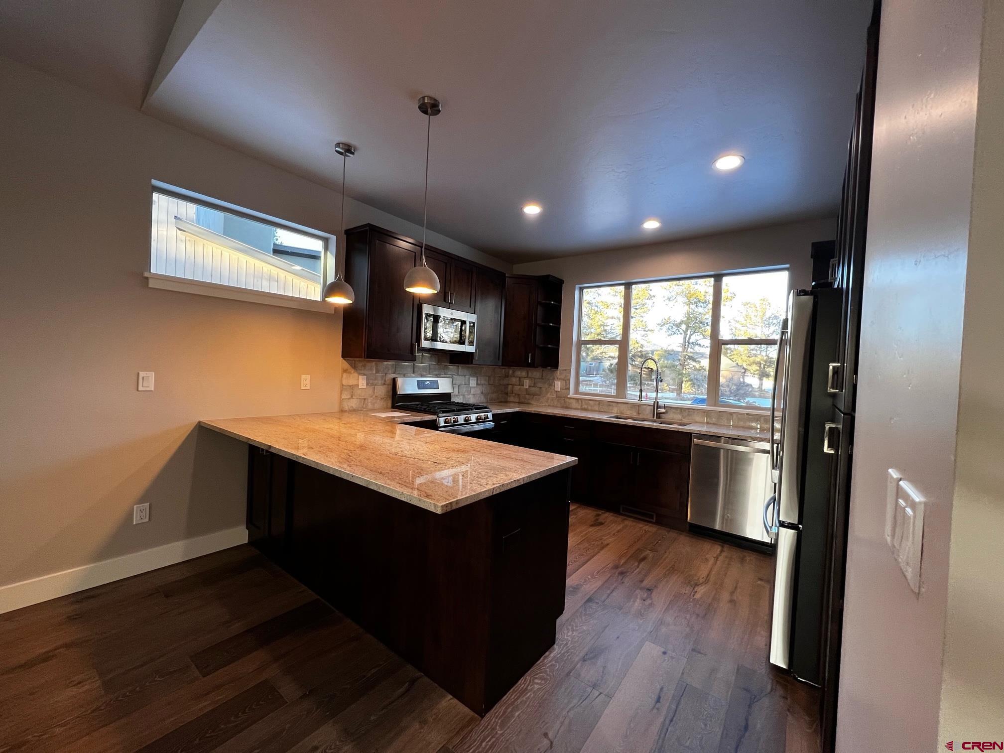 250 Edgemont Meadows Road Durango, CO 81301 - Photo 2 of 10 a kitchen with kitchen island granite countertop a sink window and wooden floor