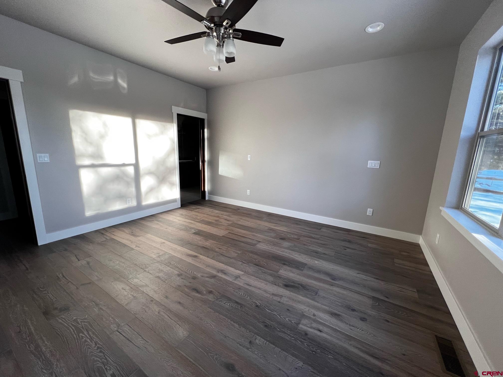 250 Edgemont Meadows Road Durango, CO 81301 - Photo 4 of 10 an empty room with wooden floor fan and windows