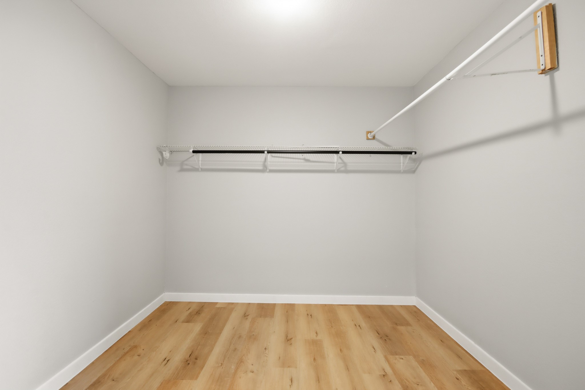 10430 Wiggins Street Houston, TX 77029 - Photo 16 of 27 Primary Spacious walk-in closet with new light laminate flooring, neutral walls, and a hanging rod with a shelf for ample storage.