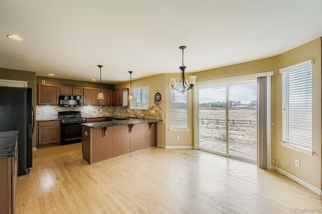 a kitchen with stainless steel appliances kitchen island granite countertop a refrigerator a sink a stove and white cabinets with wooden floor