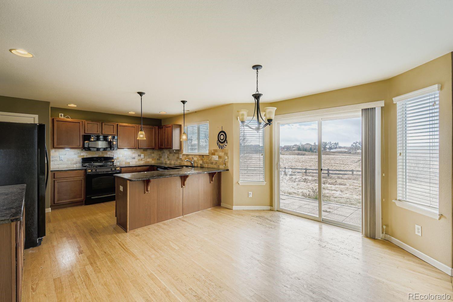 166 Bittern Drive Johnstown, CO 80534 - Photo 12 of 28 a kitchen with stainless steel appliances kitchen island granite countertop a refrigerator a sink a stove and white cabinets with wooden floor